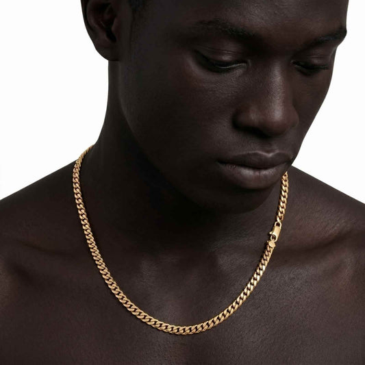 Studio close-up shot of a shirtless male model looking down, showcasing the iceX 7mm gold Miami Cuban chain and clasp detail against a white background.