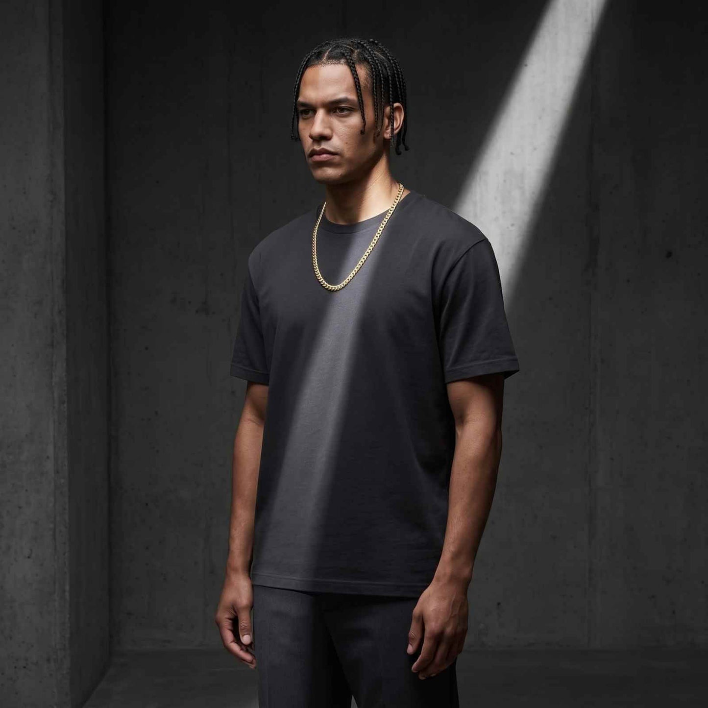 Medium shot of a male model with braids wearing the iceX 9mm gold Miami Cuban chain with a dark grey t-shirt.